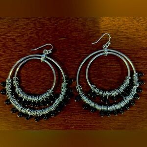 Large silvertone dangle hoop earrings with dangling black beads